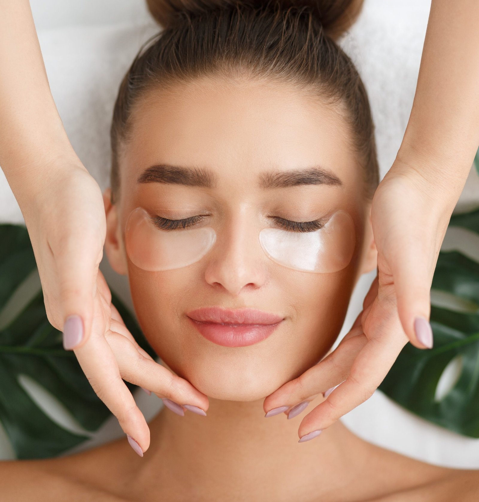 Woman with eye patches having face massage